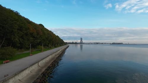 Vol aérien au-dessus des eaux calmes sur le boulevard de bord de mer de Gdynia. Dolly Forward