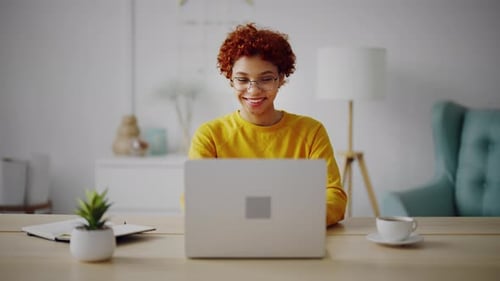Smiling Young Adult Uses Laptop at Home