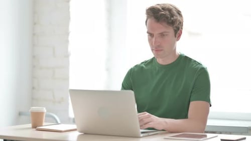 Young Man Reacting to Loss While Working in Office