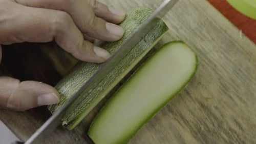 Chef Slicing Fresh Zucchini On Wooden Cutting Board Close Up