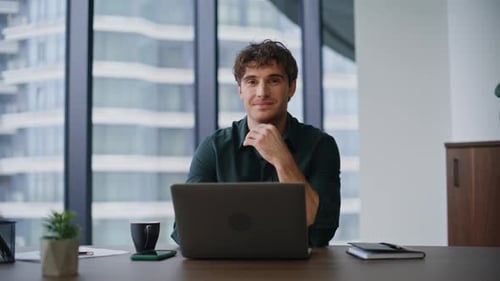 Smiling Man Typing on Laptop in Modern Office