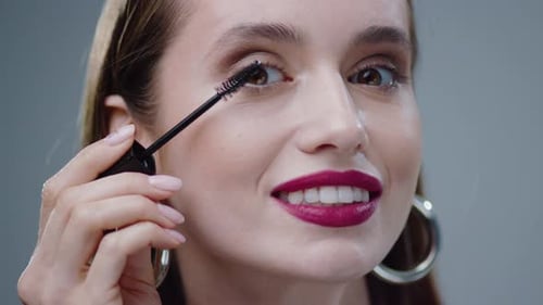 A Woman Skillfully Applying Mascara While Showcasing Her Glamorous and Stunning Makeup Look