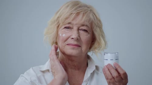 Radiant Senior Woman Applying Skincare Cream to Face