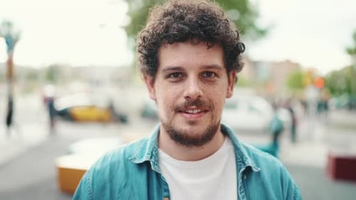 Smiling Man With Curly Hair in Urban Setting