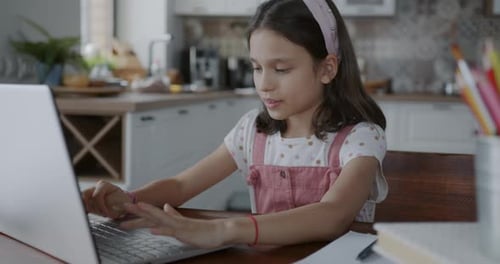 Girl Typing at Laptop in Kitchen at Home