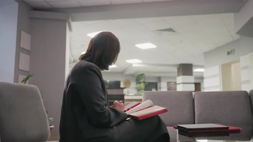 Businesswoman Reading Notebook in Office Lounge Calm Professional Setting