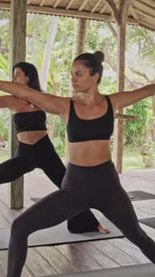 Women Practicing Yoga in Tropical Studio