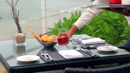 At a Sea View Restaurant a Waiter Serve a Table with Glasses of Alcohol Drinks