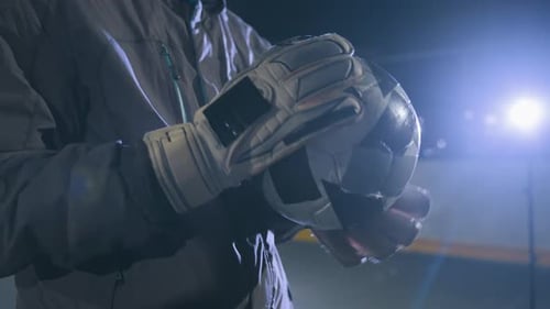 Person Holding Soccer Ball with Goalie Gloves at Night
