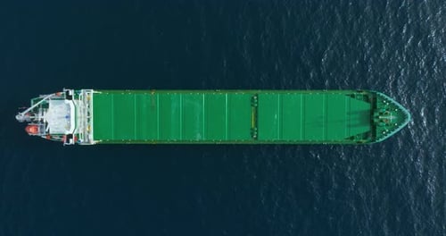 Aerial Top Down View of a Bow From a Large Cargo Ship Traveling with Speed Over Blue Ocean