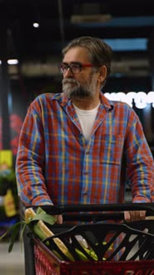 Senior Man Pushing Shopping Cart in Supermarket Aisle
