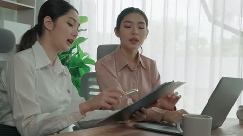 Two young enthusiastic businesswoman working together in the office workspace.