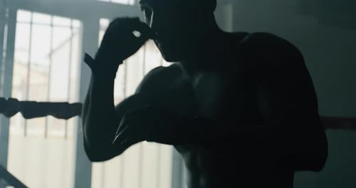 Cinematic shot of a professional young muscular shirtless african man is practicing shadow boxing