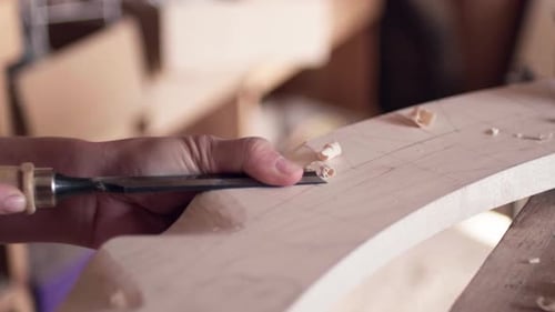 Woodworker Carefully Chiseling Wood in Indoor Workshop