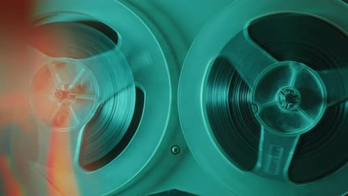 Rotating Reels of Old Analog Tape Recorder in Blue Neon Light