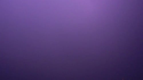 Flashes of lightning in the night sky among thunderclouds.