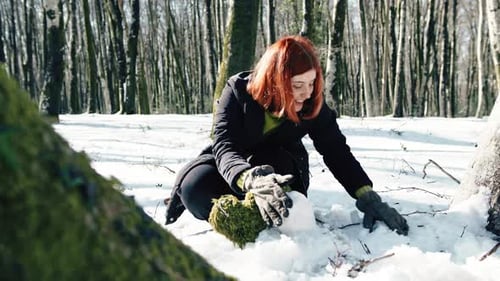Woman Making Snowball in Snowy Winter Forest