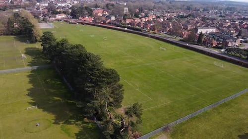 Top rotating aerial view on lush green football field hidden in forest. Public city park with sport