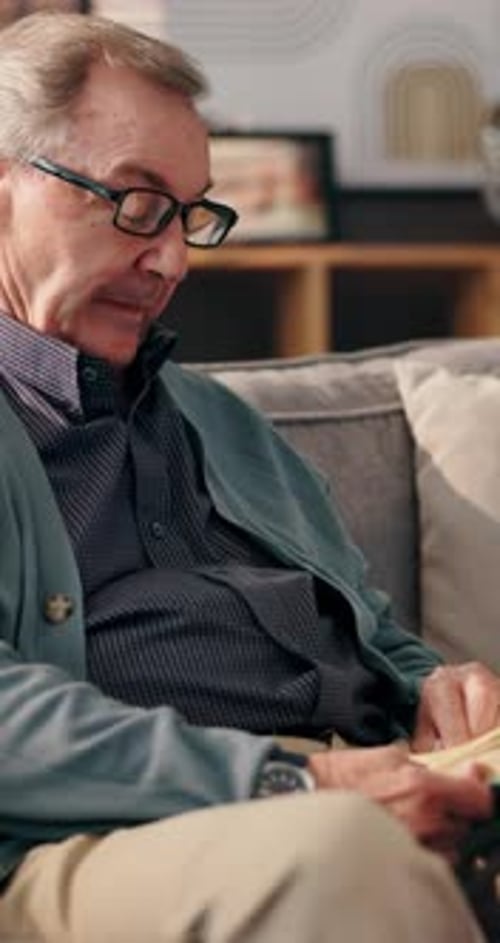 Senior Man Reading Book on Gray Couch