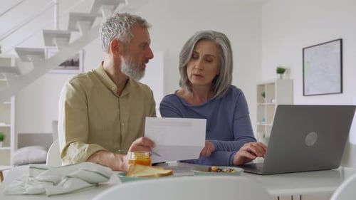 Couple Discussing Bills Using Laptop At Home