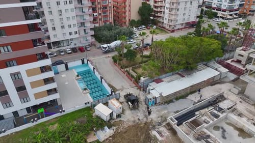 Aerial Video A Tractor with a Bucket Levels the Soil at the Construction Site Preparing the Ground