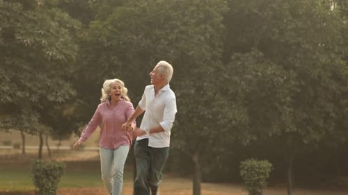 Senior Citizen Couple Enjoys Playful Run in A Sunny Park Setting