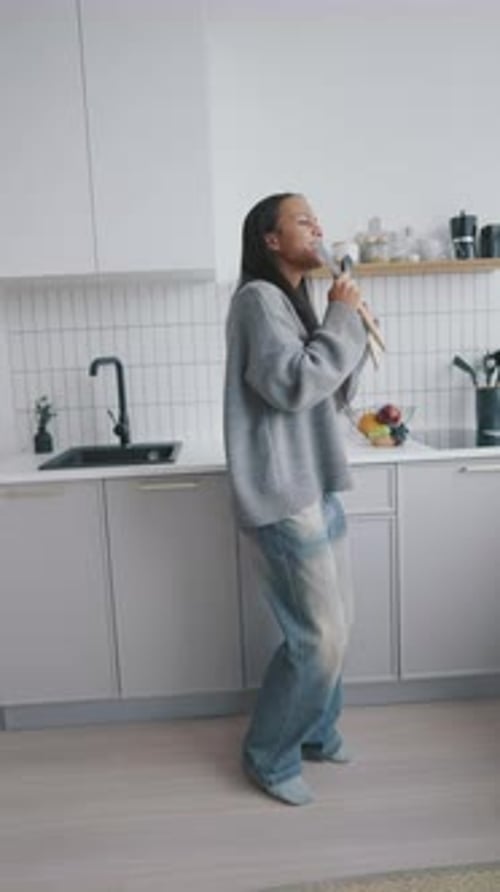 Excited Woman Singing and Dancing with Spoons in Kitchen