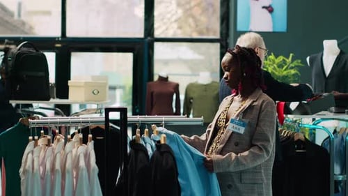 Smiling Store Employee Sorting Through Rack of Clothing