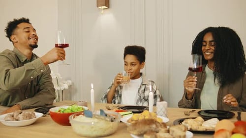 Family Toasting Drinks Together at Dinner Table