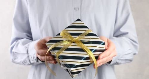 Woman Holds Striped Gift with Gold Ribbon