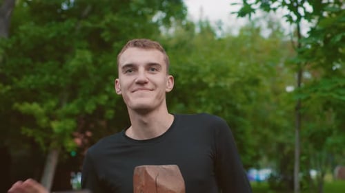 Male with Casual Grin By Trees Snapping Picture with Cheerful Expression Outdoors Happy Man in Black