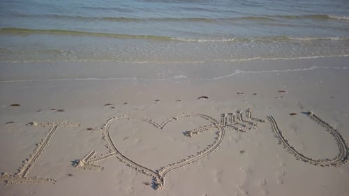 Statische Aufnahme von I Love You, eingraviert in den Sand eines Strandes.