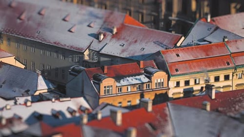 Bright-colored buildings with red roofs are on the streets of Prague. A light cover of fresh snow on