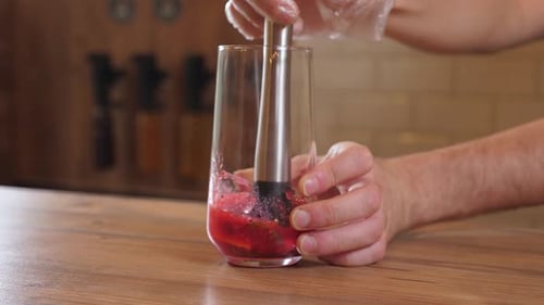 O barman espremendo o suco de um limão em um copo com um misturador