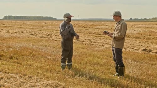 Two Farmers using Device in Wheat Field