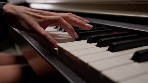 Close-up of a woman's hands in silver rings playing beautiful lyrical melody on the piano keys