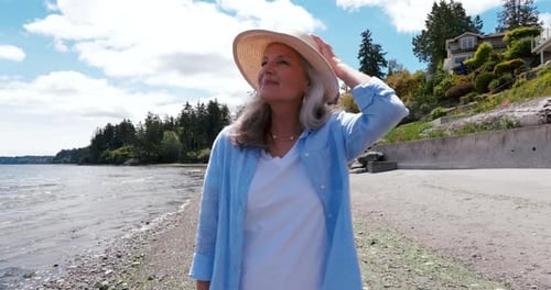 Portrait Smiling Senior Woman in Sun Hat Walking on Sunny Ocean Beach 5559 Years