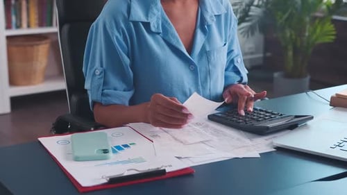 Closeup of Female Auditor's Hand with Calculator and Cashier's Checks at Table
