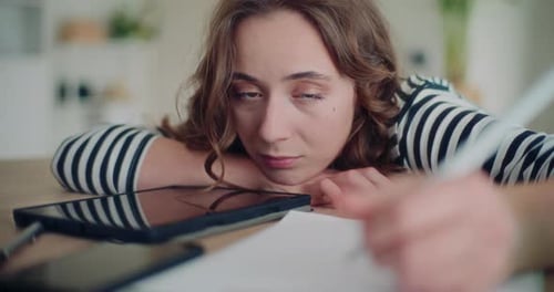 Tired Young Woman Writing at Table Close Up