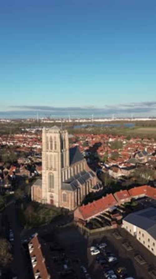 Aerial view of a historic town with a tall Gothic church in the center. Red-roofed houses