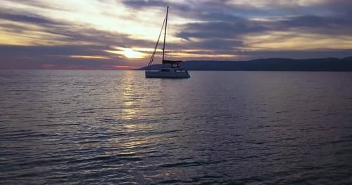Sailing yacht anchored near by cliffs in the Mediterranean sea during sunset