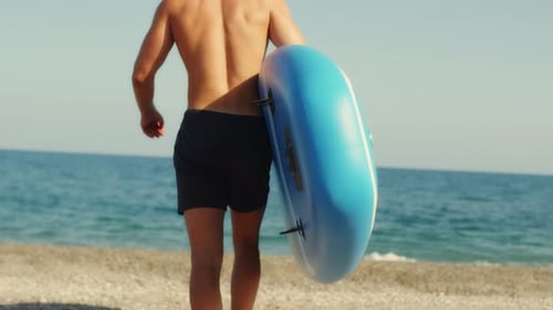 Man Walks on the Beach with Stand Up Paddle
