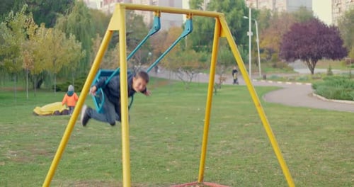 Boy Swinging on Swing Child Having Fun Playing in Outdoor Public Playground