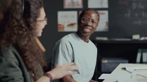 Jeune étudiant noir discutant de ses devoirs avec un camarade de classe pendant un cours d'anglais