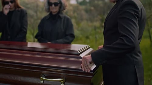 Mourners at Funeral Service Carrying Coffin