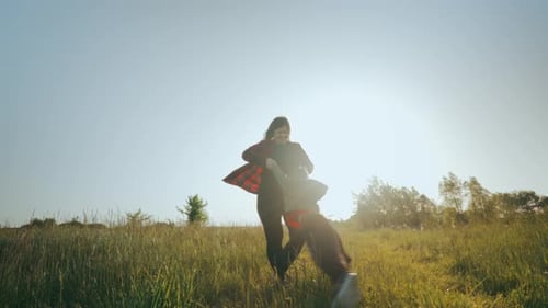 Woman Spinning a Child in a Grassy Field