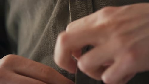 Man Buttoning Up a Green Collared Shirt Close Up