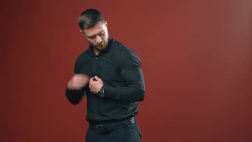 Confident businessman in stylish wear. Handsome man with beard posing on camera in dark red studio.