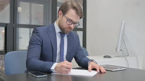 Man Writing at Desk in Modern Office