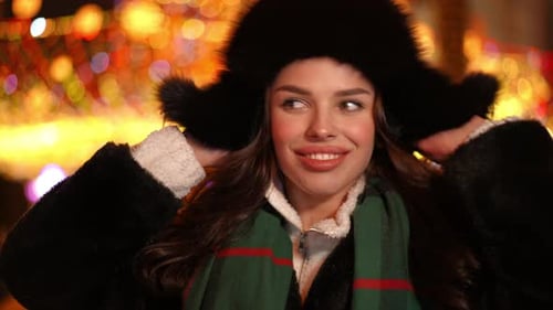 Une jeune femme caucasienne brune positive portant un chapeau de fourrure en regardant la caméra